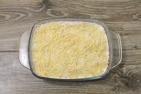 把奶酪放在中等强度的烤架上 把砂锅的顶部均匀地铺上一层 — 图库照片