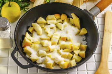 Elmaları suyla durula ve ikiye böl. Tohum bloklarını kes ve orta küp şeklinde kes. Kesiği bir tavaya ya da kazana dök, şeker ekle..