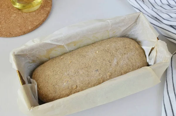 Remove the dough from the bowl, knead on the table for a couple of minutes to release the air from it. My bread pans have lost their non-stick function, so I put siliconized parchment in them. Form a loaf of bread, put in a mold. Cover and leave warm