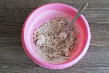 Mangırı çatalla yoğurmaya başla. Hamur toplara dönüşmeye başladığında ellerinle yoğur. Önceden bol bol sebze yağı ile yağlayın..