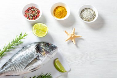 Çiğ taze Dorada beyaz ahşap bir masada baharatlı, biberiyeli, 