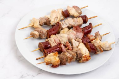 Tahta ızgarada dilimlenmiş sosis ve et var.