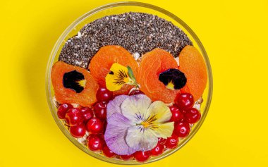 Kırmızı böğürtlenli yulaf ezmesi, kurutulmuş kayısı, çim çekirdeği ve çiçek.