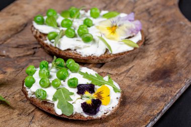 Yeşil bezelyeli peynirli sandviç ve eski ahşap bir B 'de çiçekler.