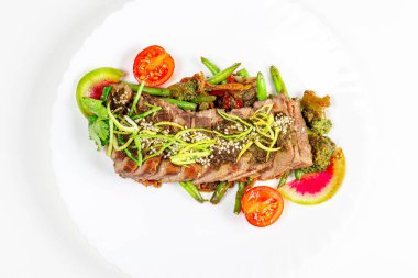 Sebzeli sığır filetosu ve beyaz tabakta baharatlı sos.