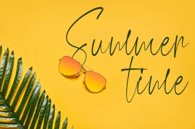 Güneş gözlüğü ve palmiye yaprağı ile aydınlık yaz arkaplanı