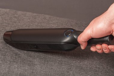 Elinde taşınabilir elektrik süpürgesi olan bir adam temizlik yapıyor.