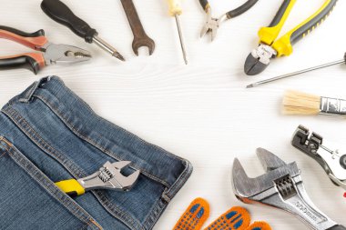 Top view, frame from work tools, glove and jeans on wooden backg