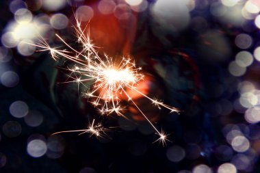 Noel arkaplanı: ellerin arka planında yanan maytap, yakın plan, bokeh