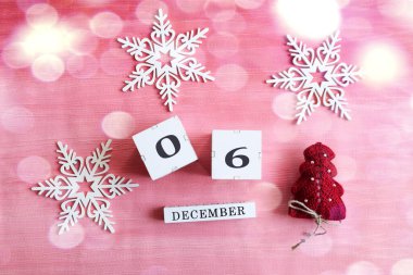 6 Aralık takvimi: 0 ve 6 numaralı küpler, İngilizce ayın adı, dekoratif kar taneleri ve pembe arka planda bir Noel ağacı, bokeh