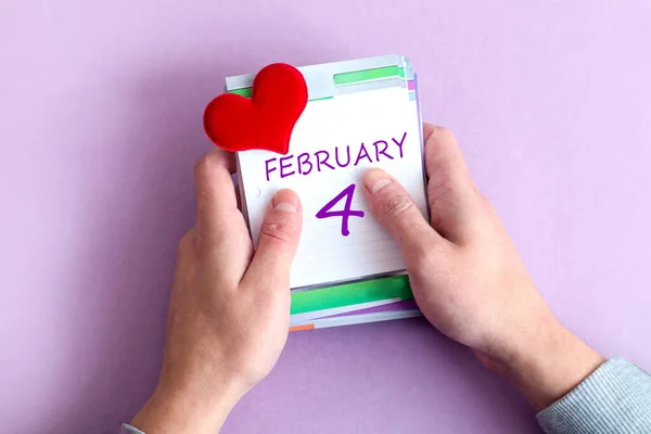 二月四日日历 手握一张活页日历 上面写着一个月的名字 数字3 粉刷背景 — 图库照片