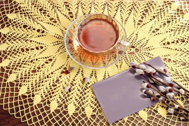 İlkbaharın gelmesiyle birlikte: bir buket söğüt ağacı sarı peçete, bir kartpostal, bir fincan çay, üstten manzara, bir yazı için bir yer.