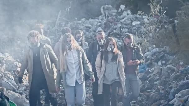 在垃圾堆中通过有毒烟雾的防毒面具中的一群年轻人。人们关心生态。反对污染行动的年轻积极分子呆在垃圾填埋场。拯救地球. — 图库视频影像