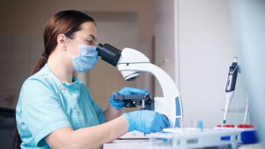 Laboratuvarda mikroskop kullanan bir bilim adamı. Coronavirus 'a karşı aşı arayışında