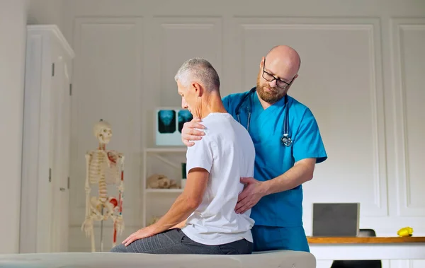 En vuxen man tränar muskelstyrka med en professionell läkare på en modern rehabiliteringsklinik. Sjukgymnastikprogram, rehabilitering efter medicinsk skada. Hälso- och sjukvårdskoncept — Stockfoto