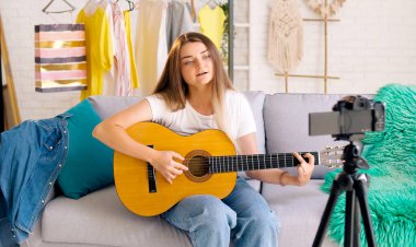 Gitarda Çalarken Çekici Genç Kız Vloglama. Çekici Genç Kız Videosunu Çekerken Konuşuyor ve Gitarla Oynuyor. Genç ve Güzel Vlog yazarı Müzik hakkında konuşuyor.