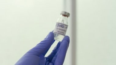 Yakın plan. Bir doktorun elinde COVID-19 Coronavirus Aşısı olan bir ilaç.