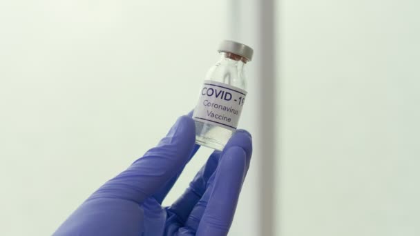 Close-up. um frasco para injetáveis com a vacina contra o Coronavírus COVID-19 na mão de um médico — Vídeo de Stock