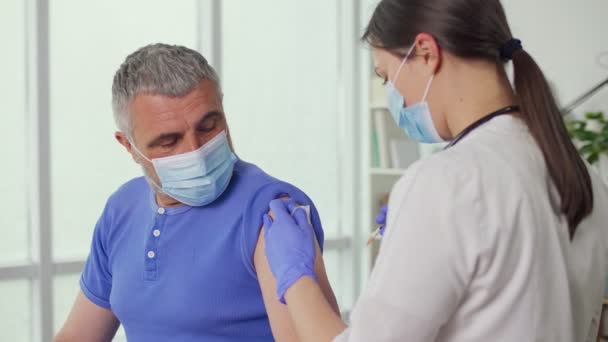 En äldre man bär en skyddande mask vaccineras mot — Stockvideo