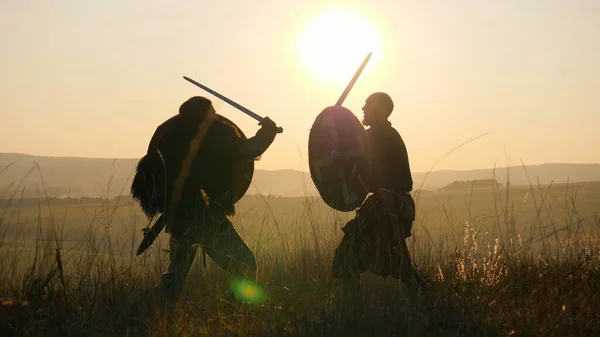Siluety válečníků Viking bojují s meči a štíty. Contre-jour — Stock fotografie