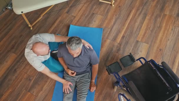 Fisioterapeuta conduzindo uma sessão de reabilitação para um homem com um derrame cerebral — Vídeo de Stock