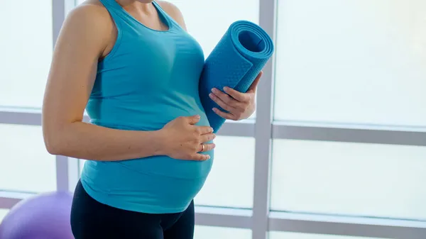 Närbild av en gravid kvinna Belly med en sportmatta. — Stockfoto