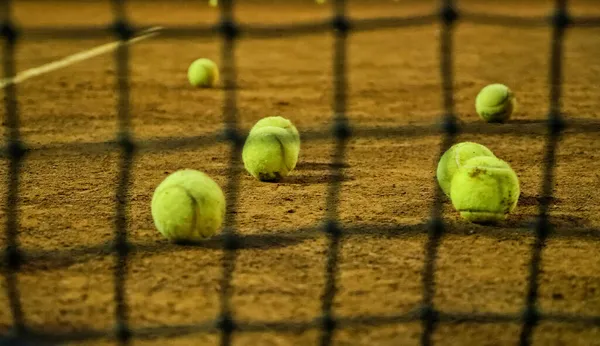 Las pelotas de tenis se encuentran en la pista de tenis. Rejilla borrosa en primer plano . —  Fotos de Stock