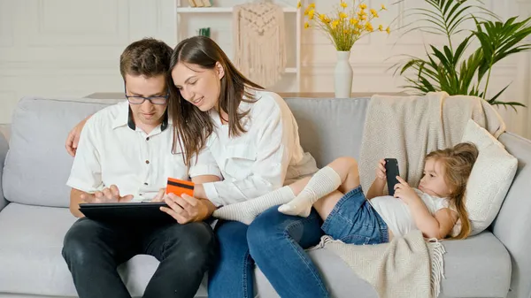 Rodzice zakupy online, podczas gdy ich córka gra w telefon gra online — Zdjęcie stockowe