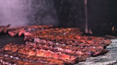 Barbekü ızgara et. Sulu domuz kaburgaları ızgaranın ızgarasında kızartılıyor, Şef kaburgaları Spatula ile çeviriyor..