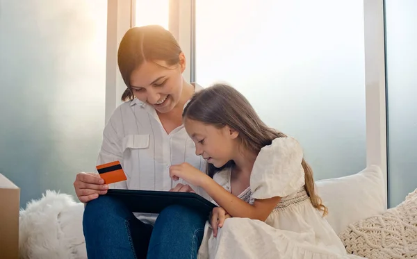Matka z dzieckiem używa karty kredytowej do zakupów online. Potwierdzenie zakupu online. Używa tabletu do zakupów online. — Zdjęcie stockowe