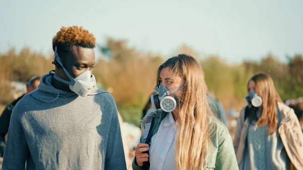 가스 마스크를 입은 청소년 그룹 이 쓰레기 더미에서 독성 연기를 뚫고 지나가고 있다. 사람들은 생태학에 관심이 있다. 지구를 구하려면. 로열티 프리 스톡 사진