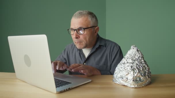 Dizüstü bilgisayarın başında oturan korkmuş bir adam Koruyucu folyo kapağını takıyor.. — Stok video