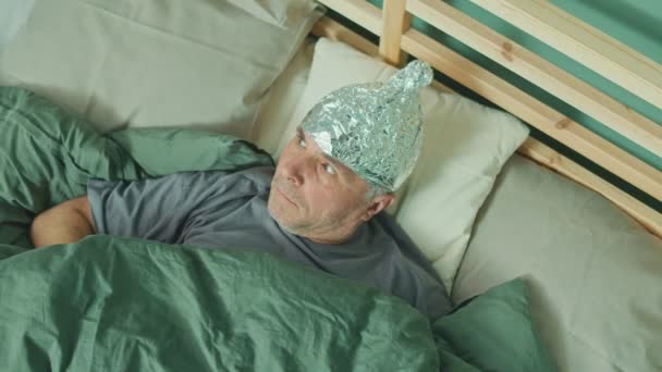 Człowiek w foliowej czapce, aby chronić się przed falami uderzającymi w jego mózg 5G — Wideo stockowe