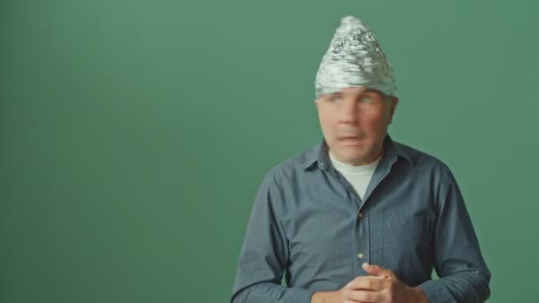Um homem paranóico com um tampão de folha protetora em sua cabeça olha ao redor ansiosamente — Vídeo de Stock