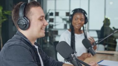 Beyaz adamla birlikte kendinden emin Afrikalı Amerikalı kadın radyo programında sunuyor.