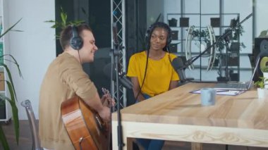 Etkili bir müzisyen radyo yayını sırasında gitar çalar ve şarkı söyler.