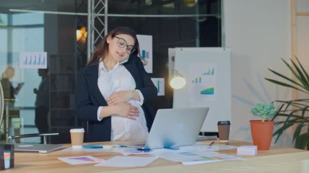 Une belle femme enceinte parlant sur un téléphone portable assis à une table — Video