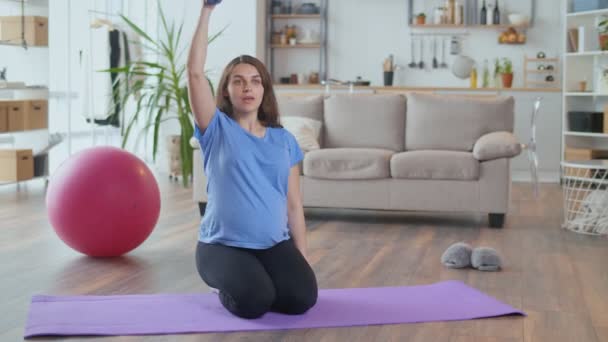 Giovane donna incinta che fa stretching e fitness in salotto — Video Stock