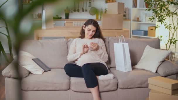 Heureuse femme enceinte reposant sur le canapé dans le salon — Video