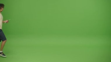 Hafif Gömlekli Genç Gezgin Meksikalı Turist Biletleri, Uçuş Geçidi ve Sarı Vagon Çantası, Tahtadaki Saate Bakıp Kontrol Ediyor ve Yeşil Ekran Arkaplanından Geri Dön