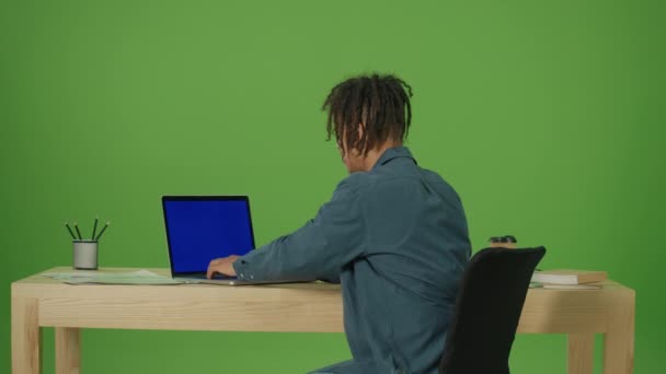 若いメキシコ人フリーランスの学生インターネットで働くブルースクリーンノートパソコンを入力し リモートジョブを実行し カメラに目を向け 笑顔と緑の画面の背景にカメラで指を指す — ストック動画