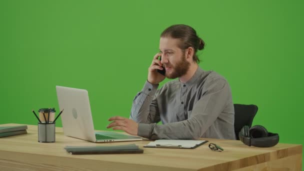 年轻而兴奋的胡子自由职业者商人在木桌上工作 在智能手机上谈情说爱 在绿色屏幕上微笑 铬钥匙 网上学习和远程工作概念 — 图库视频影像