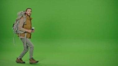 Genç Sakallı Sıcak Yelekli Turist ve Büyük Seyahat Sırt Çantası Tutma Biletleri, Karmaşık Bakış, Takvim Kontrol ve Acele Gidiş Yeşil Ekran, Krom Anahtarlı Seyahat Konsepti.