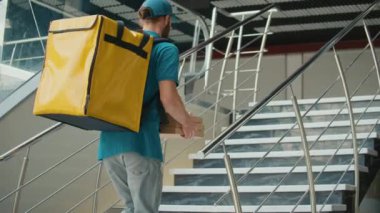Çağdaş Ofis Binasında Merdivenlerden Yukarı çıkarken Termal Sırt çantalı Pizza Kutuları ve Kahve Getiren Yemek Teslimatçısı. Kurye siparişi bir müşteriye ulaştırmak üzere yolda..