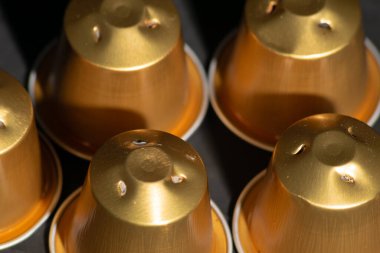 Close up image used golden coffee capsules to be recycled with dark background ,