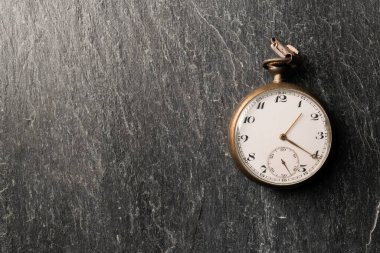 Antique clock on a white background an golden hand on a black stone background