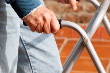 Man whose face cannot be seen walking with the aid of a walker