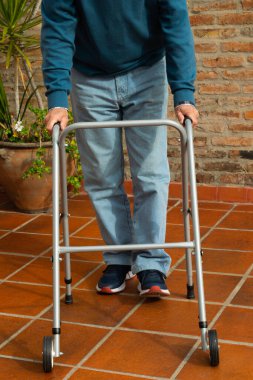 Man whose face cannot be seen walking with the aid of a walker