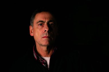 Portrait of mature men . Half illuminated face on black background