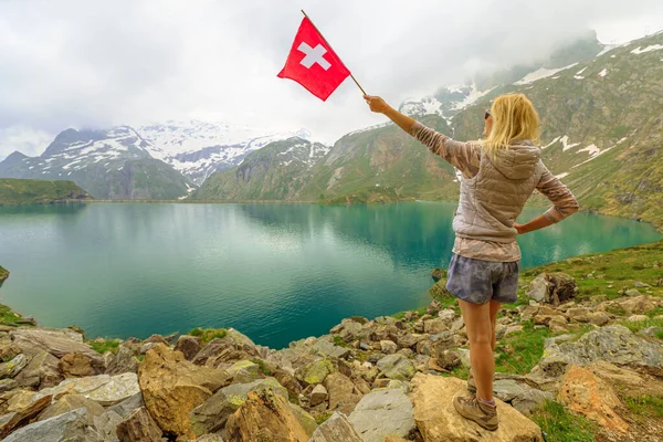 Tourist at Robiei lake with swiss flag — Stock Photo, Image